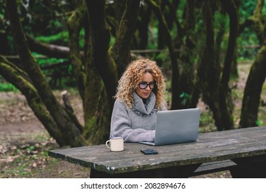 Young adult modern woman use computer laptop sitting at the table in the forest park. People with online job technlogoy and roaming connection outdoors. Pretty female write - Powered by Shutterstock