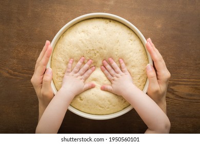 Young adult mother hands holding bowl and baby hands touching fresh white raw dough on brown wooden table background. Spending time together in kitchen. Ready for baking. Point of view shot. Closeup. - Powered by Shutterstock