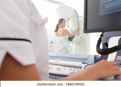 Young Adult Patient On A Mammogram Machine In Selective Focus Being Examined By A Radiologist On Monitor Wearing A Lab Coat In The Foreground