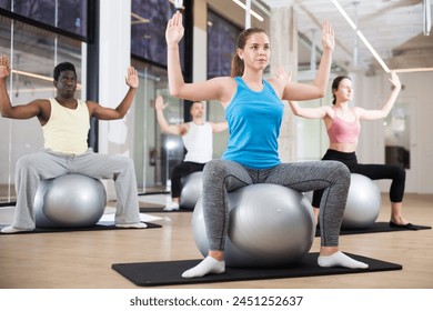 Young adult people practicing pilates with ball at group class in yoga studio - Powered by Shutterstock