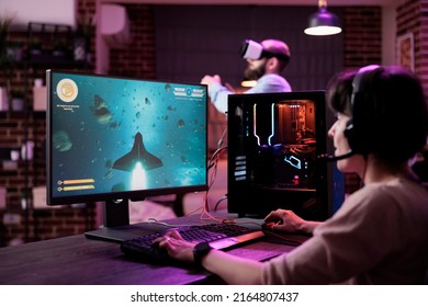 Young Adult Playing Shooter Video Games Championship On Pc, In Living Room With Neon Lights. Female Gamer Enjoying Action Gameplay Competition To Do Live Stream Online, Having Fun On Internet.