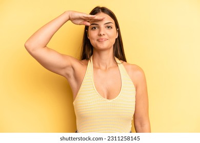young adult pretty woman greeting the camera with a military salute in an act of honor and patriotism, showing respect