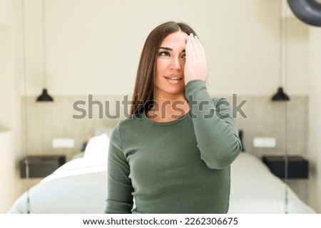 young adult pretty woman looking sleepy, bored and yawning, with a headache and one hand covering half the face