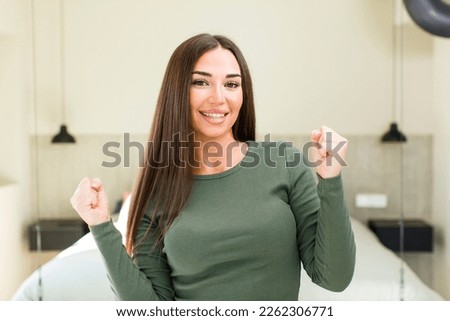young adult pretty woman looking extremely happy and surprised, celebrating success, shouting and jumping