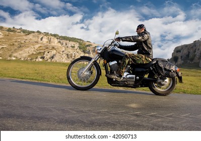 Young adult  rebel biker riding a chopper motorcycle in a remote location