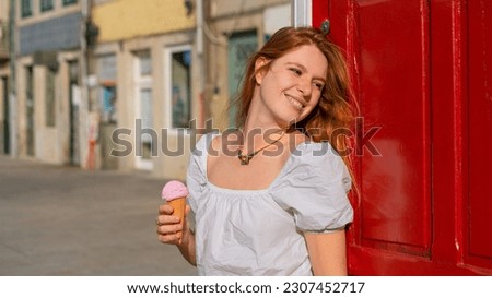 Young adult red haired woman enjoying ice cream and sunshine in the town