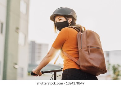 Young adult riding a bicycle through the city wearing face mask against COVID-19 - Powered by Shutterstock