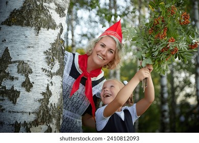 Young and adult schoolgirl on September 1, mother and daughter having fun together. Generations of schoolchildren of USSR and Russia. Female pioneer in red tie and October girl in modern uniform
