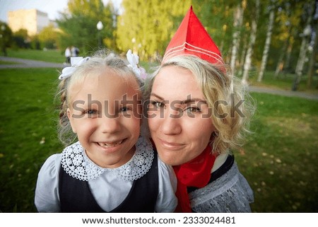 Young and adult schoolgirl on September 1. Generations of schoolchildren of USSR and modern Russia. Female pioneer in red tie and October girl in modern uniform. Mother and daughter having fun