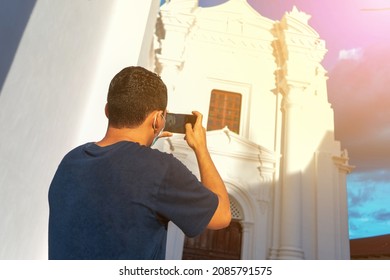 Young adult sightseeing outside a church with his smartphone texting and taking photos in a tourist spot in León, Nicaragua.