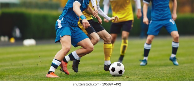 Young Adult Soccer Players Compete at the Pitch. Football League Game. Teenage Sports Players in Jersey Shirts and Cleats Kicking Black and White Soccer Ball - Powered by Shutterstock