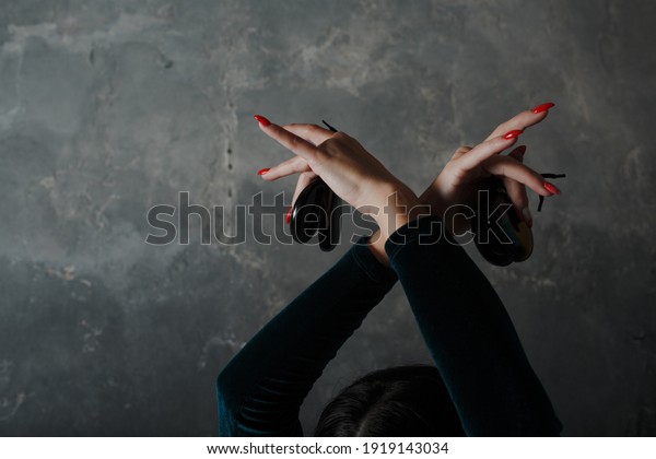 Young adult spanish woman dancing flamenco\
with castanets on gray vintage\
background
