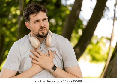 Young adult sports man runner jogger having heart attack or chest pain after running workout in urban city park. A tired athlete suffers from tension in the heart. Health care and sports concept. - Powered by Shutterstock