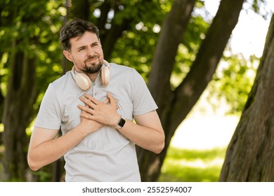 Young adult sports man runner jogger having heart attack or chest pain after running workout in urban city park. A tired athlete suffers from tension in the heart. Health care and sports concept. - Powered by Shutterstock