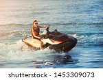 Young adult sporty caucasian woman riding jet ski in ocean blue water at warm evening sunset. Beach extreme sport activities and recreation