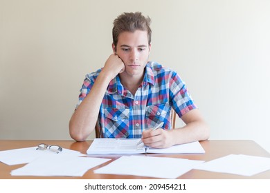 Young Adult Studying ,feeling Frustrated, In A Messy Desktop. Paper Scattered Around.