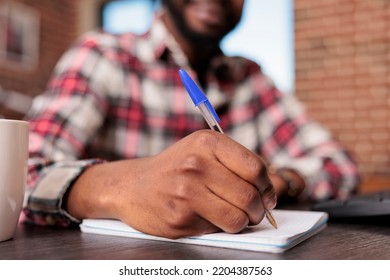 Young Adult Taking Notes On Textbook, Working With Documents And Paperwork At Home Desk. Working Remotely With Notebook And Computer To Do Online Freelance Job, Class Lesson. Close Up.