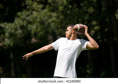 A Young Adult Throwing A Football Outside.