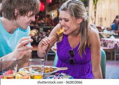 Young adult tourist couple enjoying food in outdoor cafe