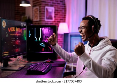 Young Adult Winning Online Video Games Tournament On Pc, Streaming Action Gameplay With Multiple Players On Internet. Male Gamer Playing Shooting Competition And Feeling Happy About Win.