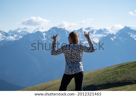 Young adult woman with back facing the camera, rocks out and headbangs at Hurricane Ridge in Olympic National Park