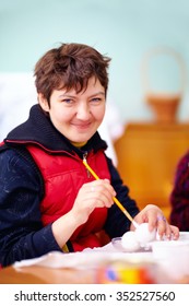 young adult woman with disability engaged in craftsmanship in rehabilitation center