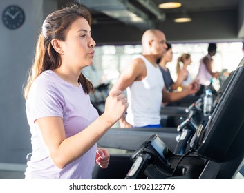 Young adult woman doing cardio workout running on treadmill at fitness center - Powered by Shutterstock