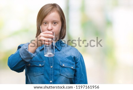 Young adult woman with down syndrome drinking water over isolated background with a confident expression on smart face thinking serious