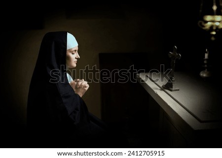 Young adult woman dressed in authentic habit and veil of a catholic nun in a medieval chapel