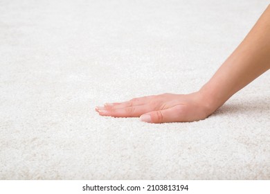 Young adult woman hand touching white new fluffy carpet surface. Closeup. Checking softness. Side view.