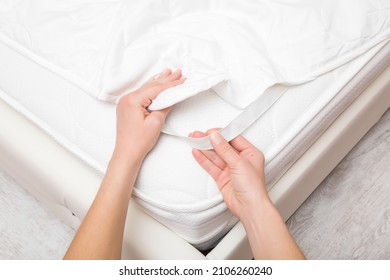 Young adult woman hands putting white cover with elastic band on mattress. Closeup. Point of view shot. Regular bed linen change. 