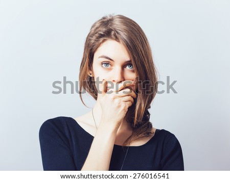 young adult woman holding hand over her mouth over grey background