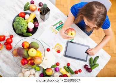 A young adult woman informing herself with a tablet PC about nutritional values of fruits and vegetables.  - Shutterstock ID 252808687