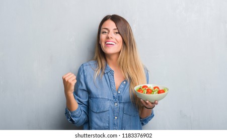 Young adult woman over grey grunge wall eating healthy tomato salad screaming proud and celebrating victory and success very excited, cheering emotion - Shutterstock ID 1183376902