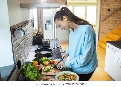 Young adult woman preparing a healthy salad in the kitchen - Powered by Shutterstock