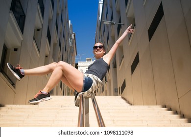 Young Adult Woman Sliding Down The Stair Railing And Smiling