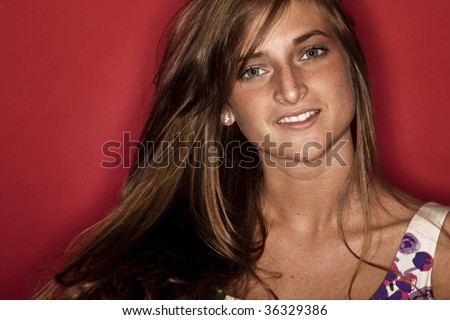 Young adult woman smiling on red background