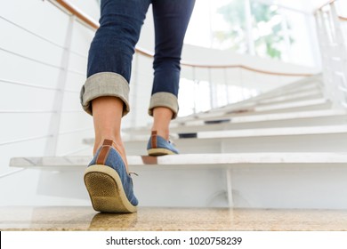 Young adult woman walking up the stairs with sun sport background. - Shutterstock ID 1020758239