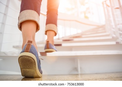 Молодая взрослая женщина поднимается по лестнице с солнечным спортивным фоном.