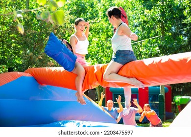 Young And Adult Women Having Pillow Fight Between Each Other In Outdoor Amusement Park During Summertime.