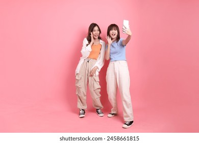 Young adults friends, 20s East Asian womentaking a selfie on the pink background.  - Powered by Shutterstock