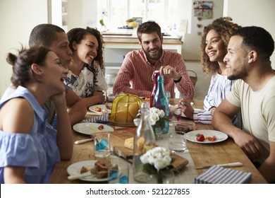 Young adults laughing as they talk at a table over lunch