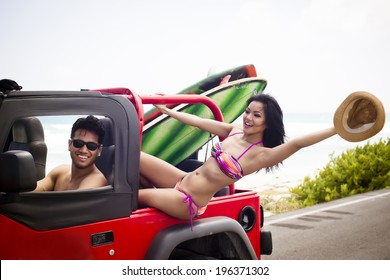 Young Adventurous Couple Ready To Surf At The Beach With A Red Car