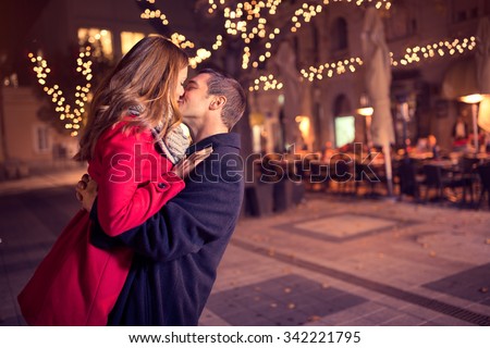 Young affectionate couple kissing tenderly on Christmas street  Сток-фото © 