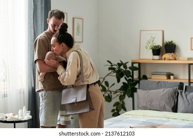 Young affectionate female kissing cute baby son on hand of her husband in the morning while saying goodbye and leaving for work - Shutterstock ID 2137612103
