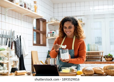 Young Afican American Woman Learning Online  Cooking Class Via Tablet Computer In Kitchen At Home