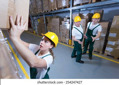 Young Afraid Woman Lifting Heavy Box In Warehouse