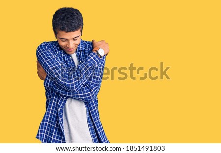Young african amercian man wearing casual clothes hugging oneself happy and positive, smiling confident. self love and self care 