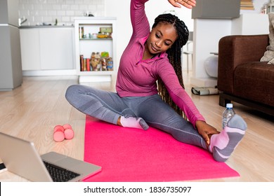 Young African America Woman At Home Doing Exercise In Front Of Open Laptop, Repeating Instructions By Professional Online Fitness Trainer.