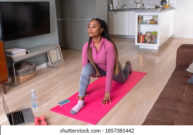 Young African America Woman At Home Doing Exercise In Front Of Open Laptop, Repeating Instructions By Professional Online Fitness Trainer.